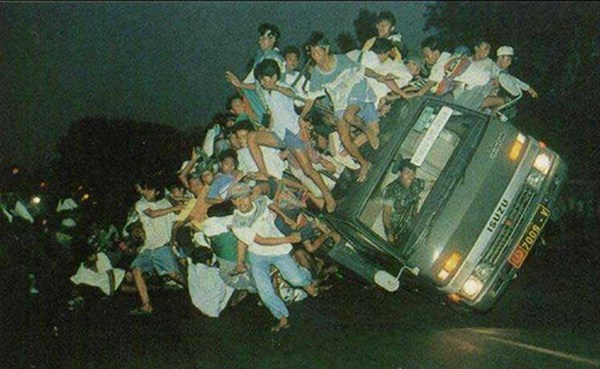 photograph of a car covered in people about to tip over, timing