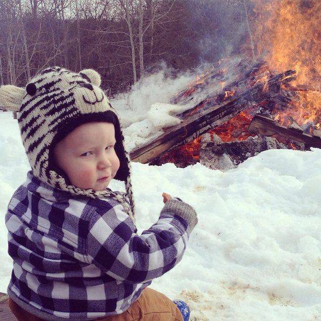 baby chilling in front of a winter camp fire