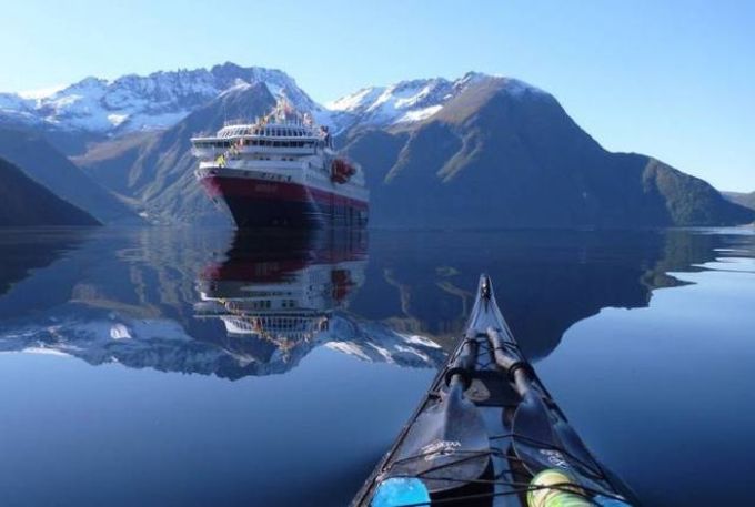 kayaking on mirror lake in the alps with a large boat in the distance