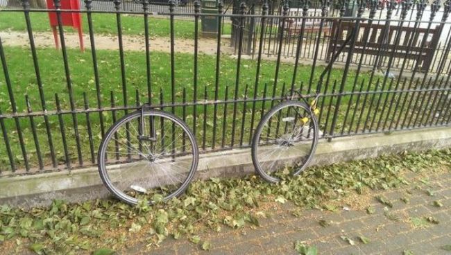 two bicycle wheels locked to a fence, suspicious