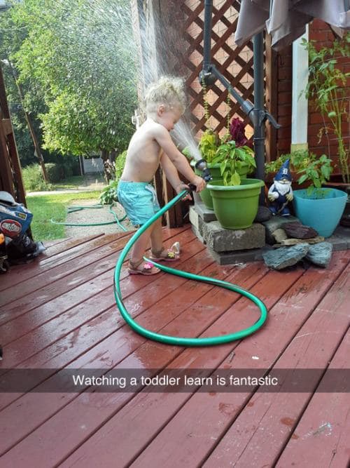 watching a toddler learn is fantastic, little kid spraying himself in the face with a hose and spray nozzle