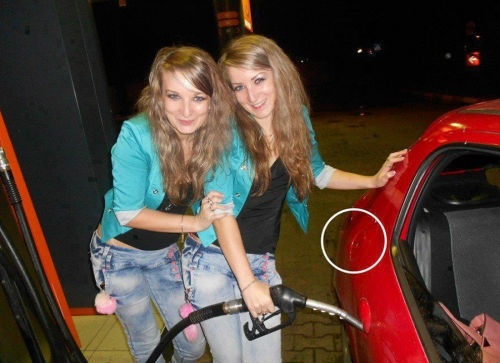 two girls posing putting gas in their car's door handle, fail