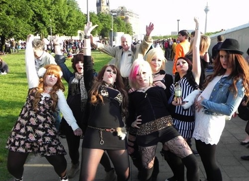 old guy photobombs punk and goth girl group photo