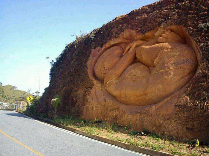 rock carving of woman in fetal position along highway, wow
