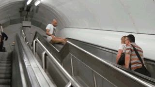 guy slides down hand rail of escalator and fails, gif