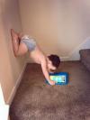 kid playing on game tablet in a strange position, legs on wall