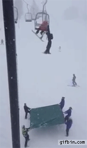 skier falls off chair lift into tarp held by ski hill personnel