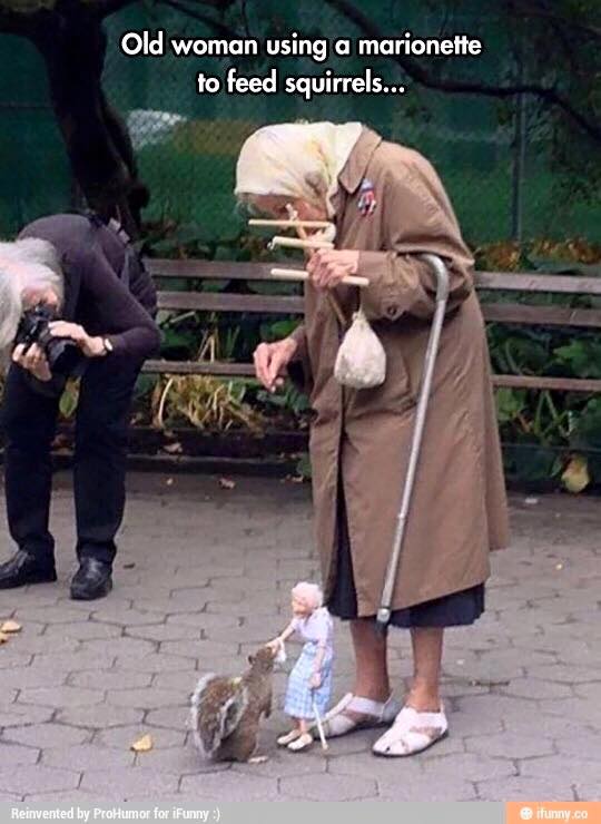 old woman using a marionette to feed squirrels
