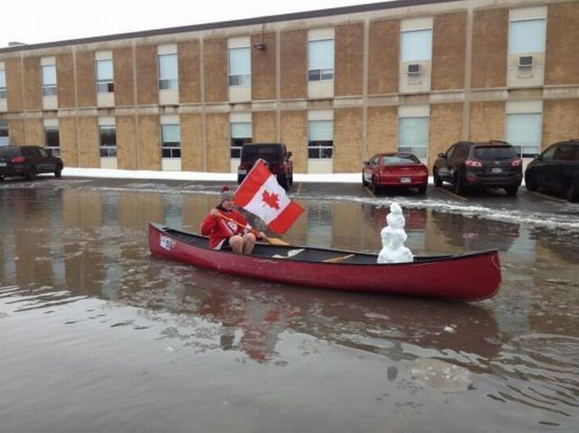 meanwhile in canada, snowman in a canoe on a flooded street