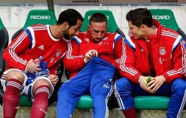 three soccer players inspecting a fellow team mate