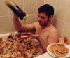after breakfast in bed, enjoy brunch in the tub, man covered in pancakes in the bathtub pouring syrup on himself
