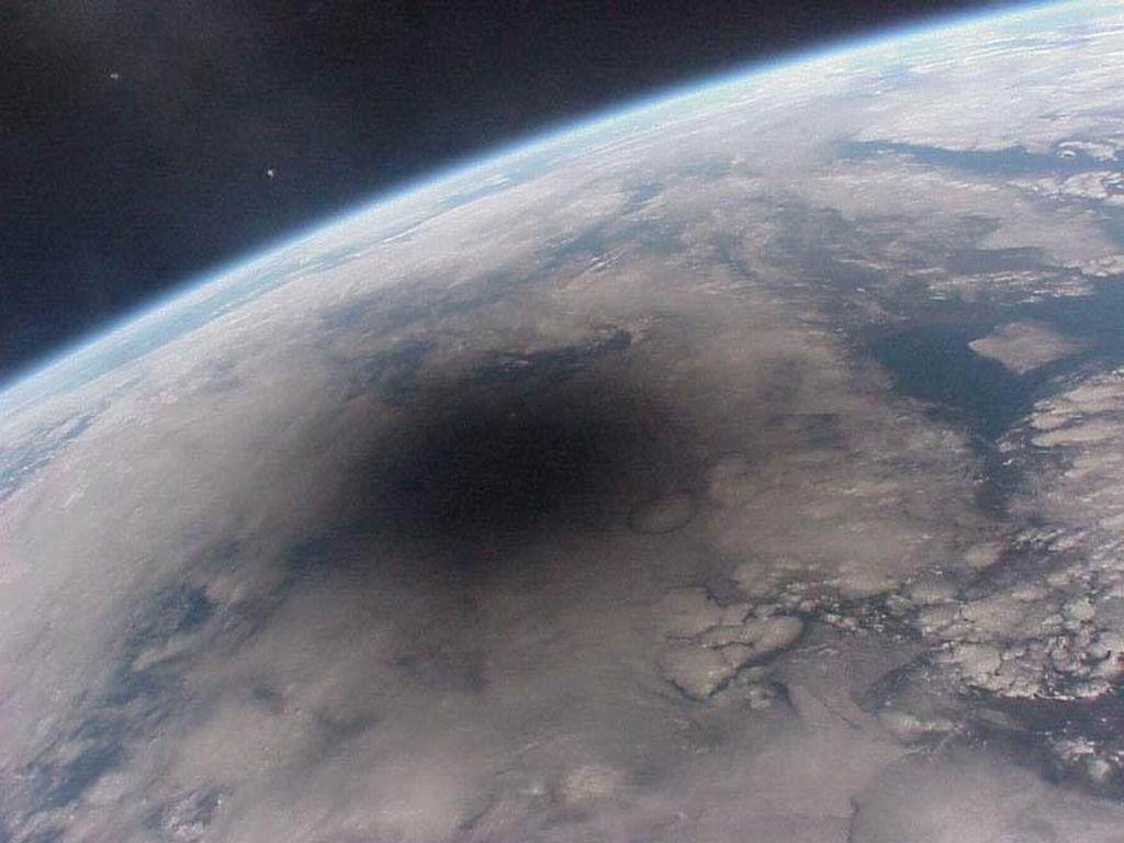 a solar eclipse as seen from space, huge shadow over the earth