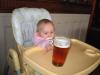 baby in high chair reaching for beer with intent look in eyes