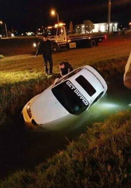 car with get dipped written on it's windshield goes for a dip in a ditch