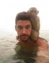 monkey standing on shoulders of man in water