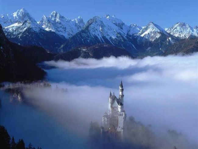 just a castle in the fog next to some epic mountains