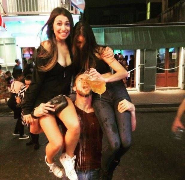 guy holding two girls and being rewarded with beer from a pitcher