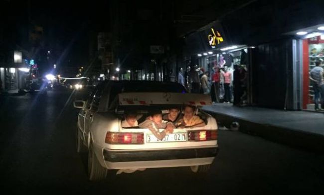 kids hanging out the back of a trunk at night, wtf