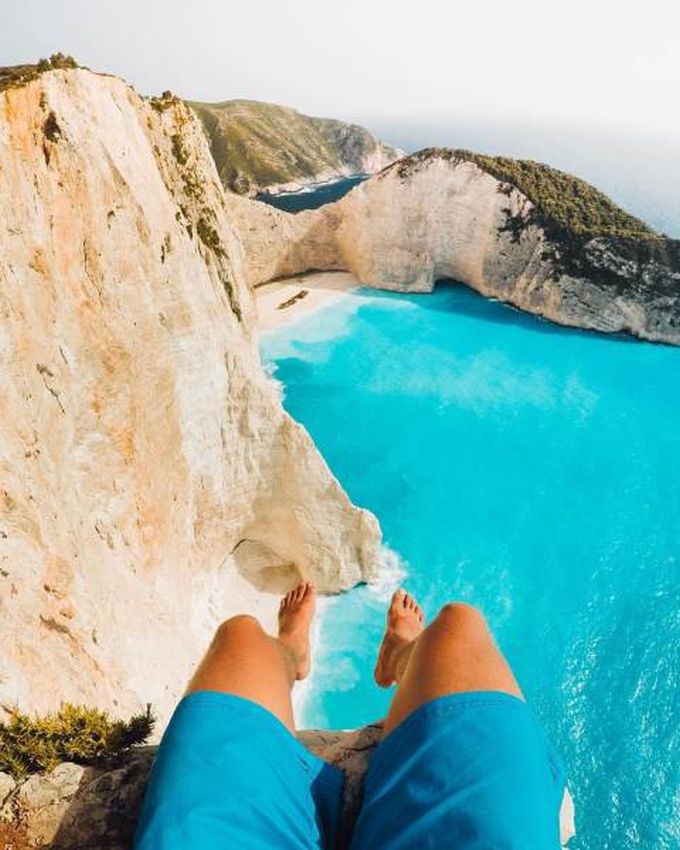 sitting on a cliff over crystal clear blue waters, nature is beautiful