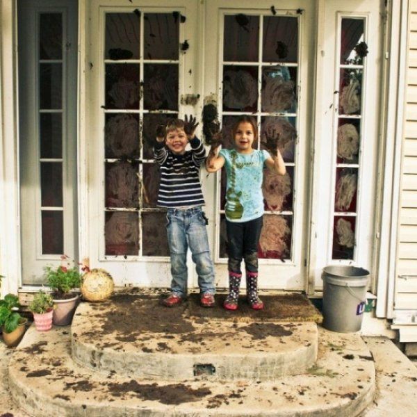 two kids showing off their mud art on the french doors