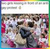 two girls kissing in front of an anti gay protest