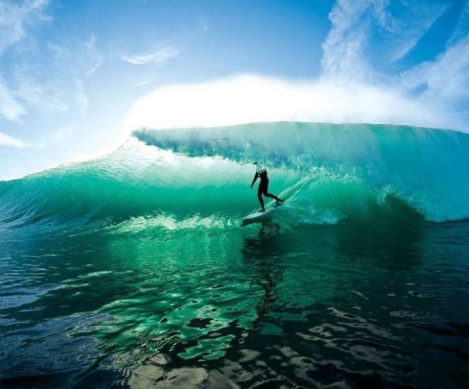surfing in crystal clear teal water waves