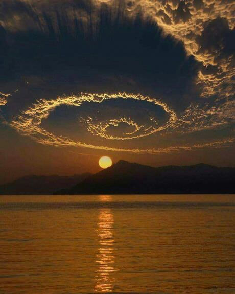 spiral cloud formation above mountain over sunset