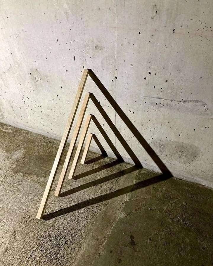 wood dowels against a wall make perfect triangles with shadows