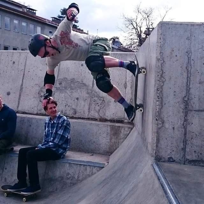 skateboarder supports self on friends head, optical illusion
